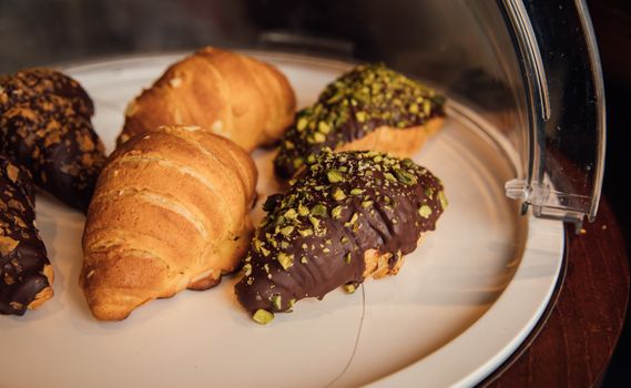 Assorted croissants with chocolate and pistachio topping on a tray.