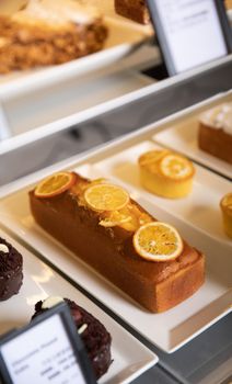 Tantalizing lemon cake with dried citrus slices adorned on bakery shelf with assorted pastries.