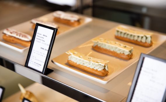 Delicious eclairs with white chocolate and yuzu cream displayed elegantly on plates.