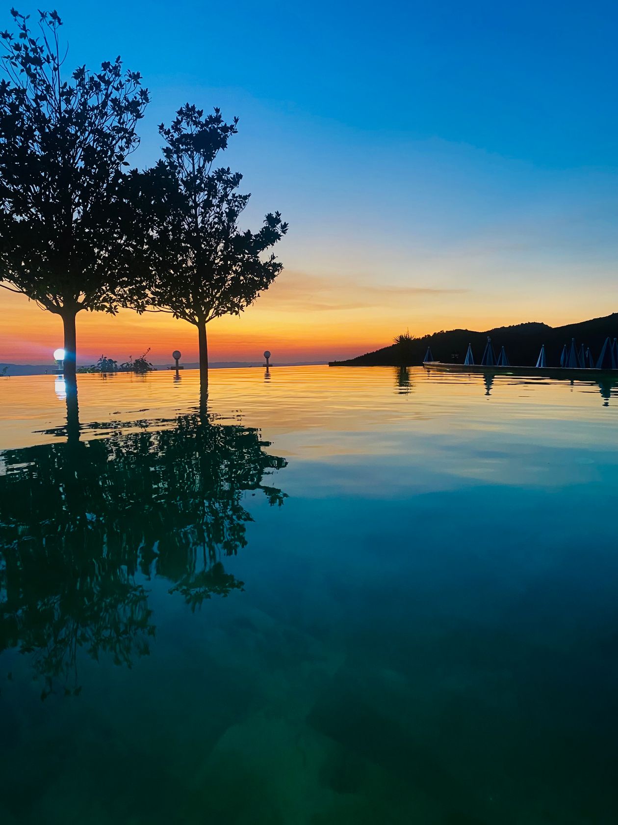 Aerial view of an infinity pool glowing at twilight sunset, drone and twilight photography combination