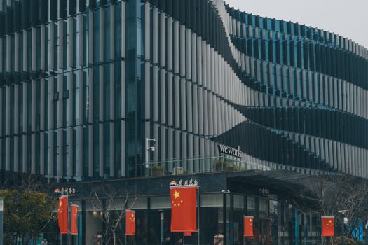 Contemporary architectural building with Chinese flags displayed prominently.