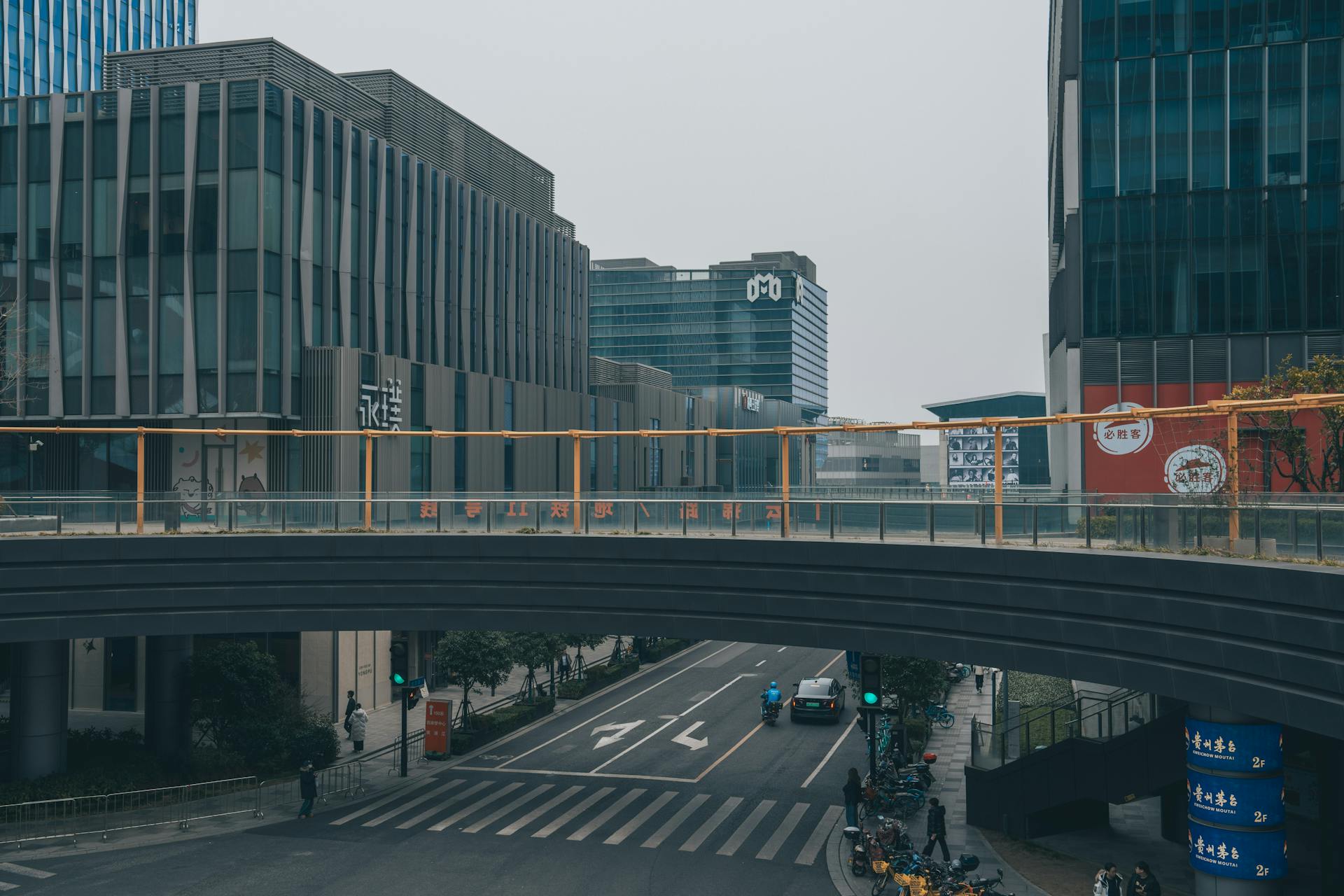 A cityscape featuring a modern street with an overpass and high-rise buildings in daylight.