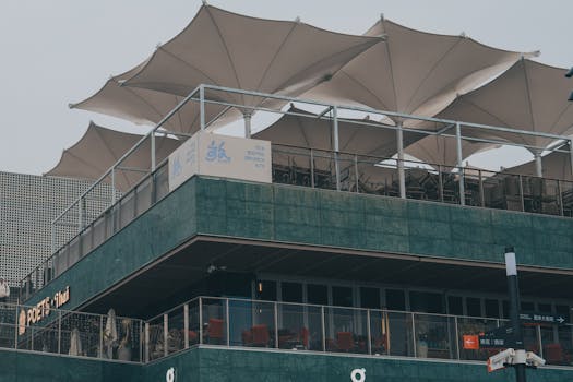 Street view of a modern rooftop restaurant with distinctive umbrella shades on a cloudy day.