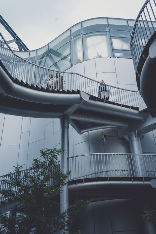 Free Futuristic metallic stairs with people ascending, showcasing modern architecture. Stock Photo