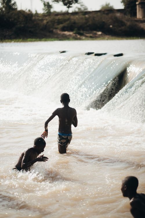 Free Joyful children playing in a flowing river on a sunny day capturing the essence of carefree childhood. Stock Photo