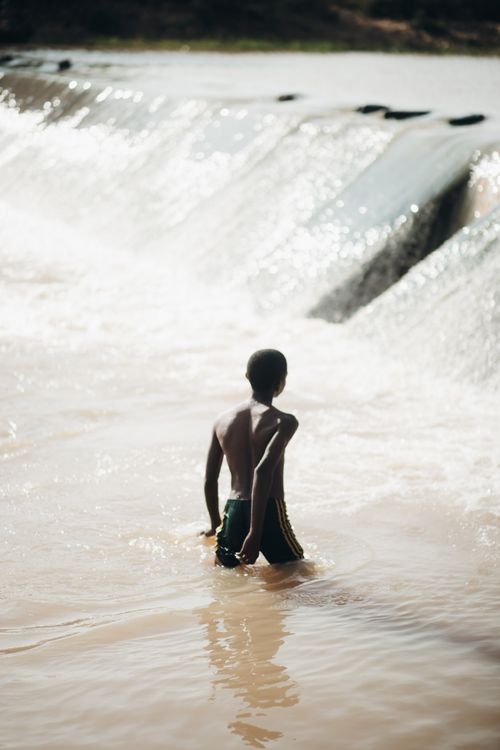 Free Young person enjoys a refreshing swim by the waterfall, embodying freedom and adventure. Stock Photo