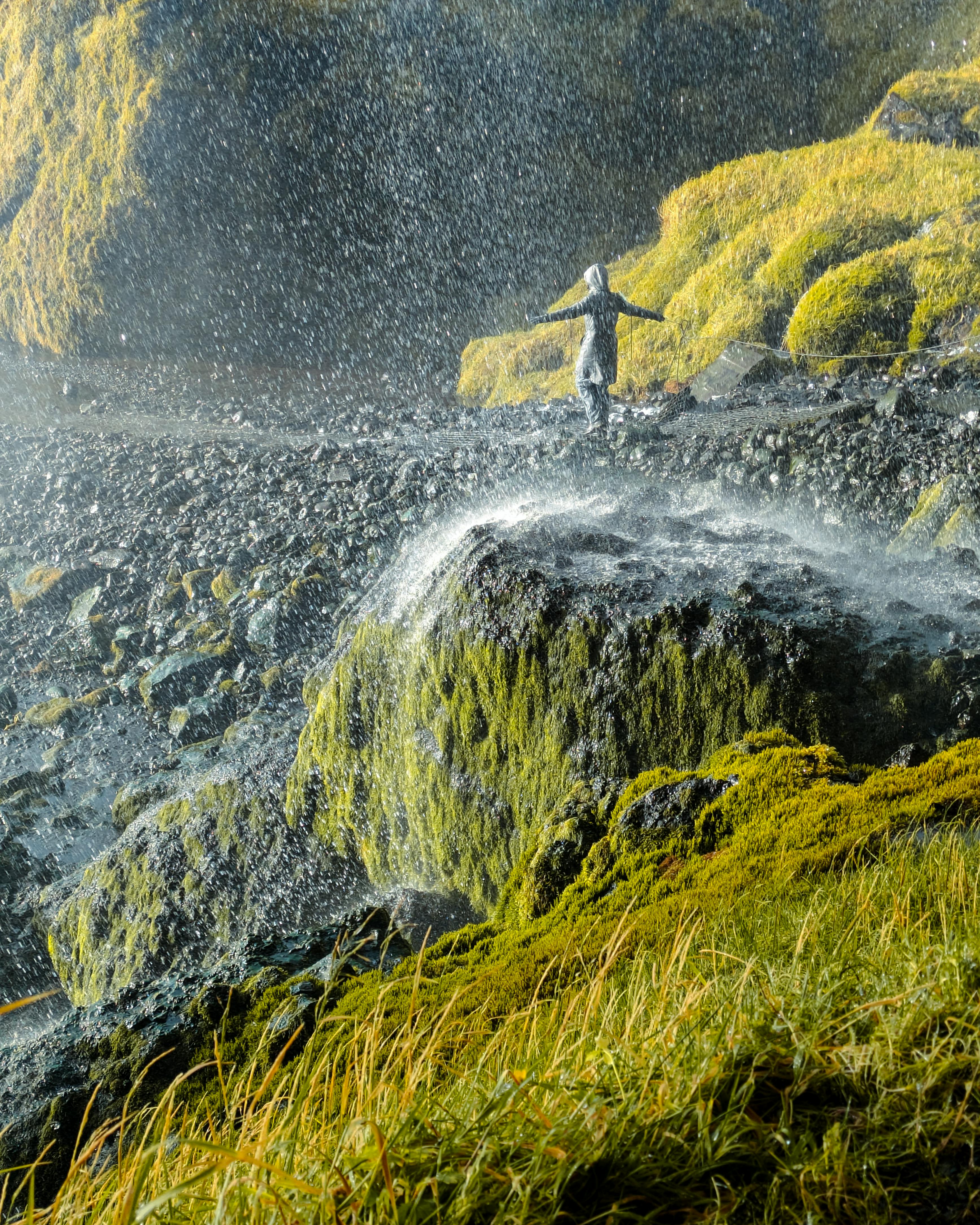 A vivid capture of a person enjoying a waterfall in Iceland's lush landscape.