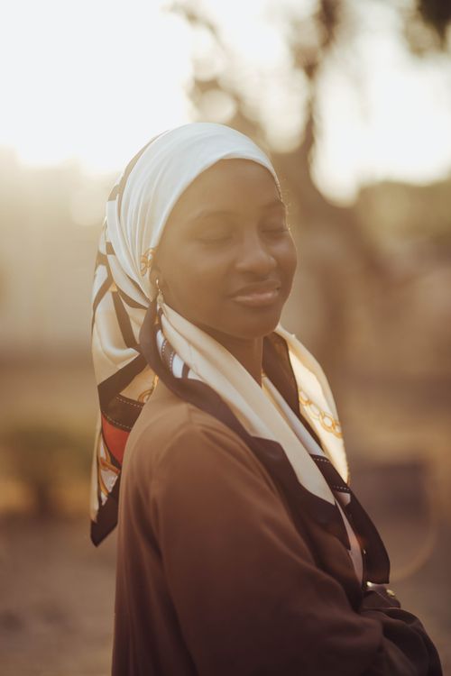 Free A peaceful portrait of a woman wearing a headscarf, bathed in warm sunlight. Stock Photo