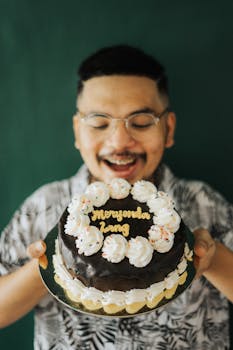 Joyful adult holding a decorated chocolate cake with birthday message.