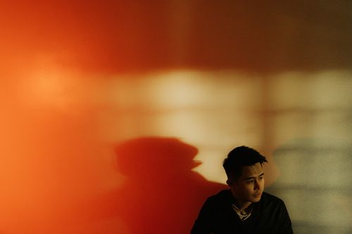 Free Moody portrait of a young man with dramatic shadows on an orange wall. Stock Photo