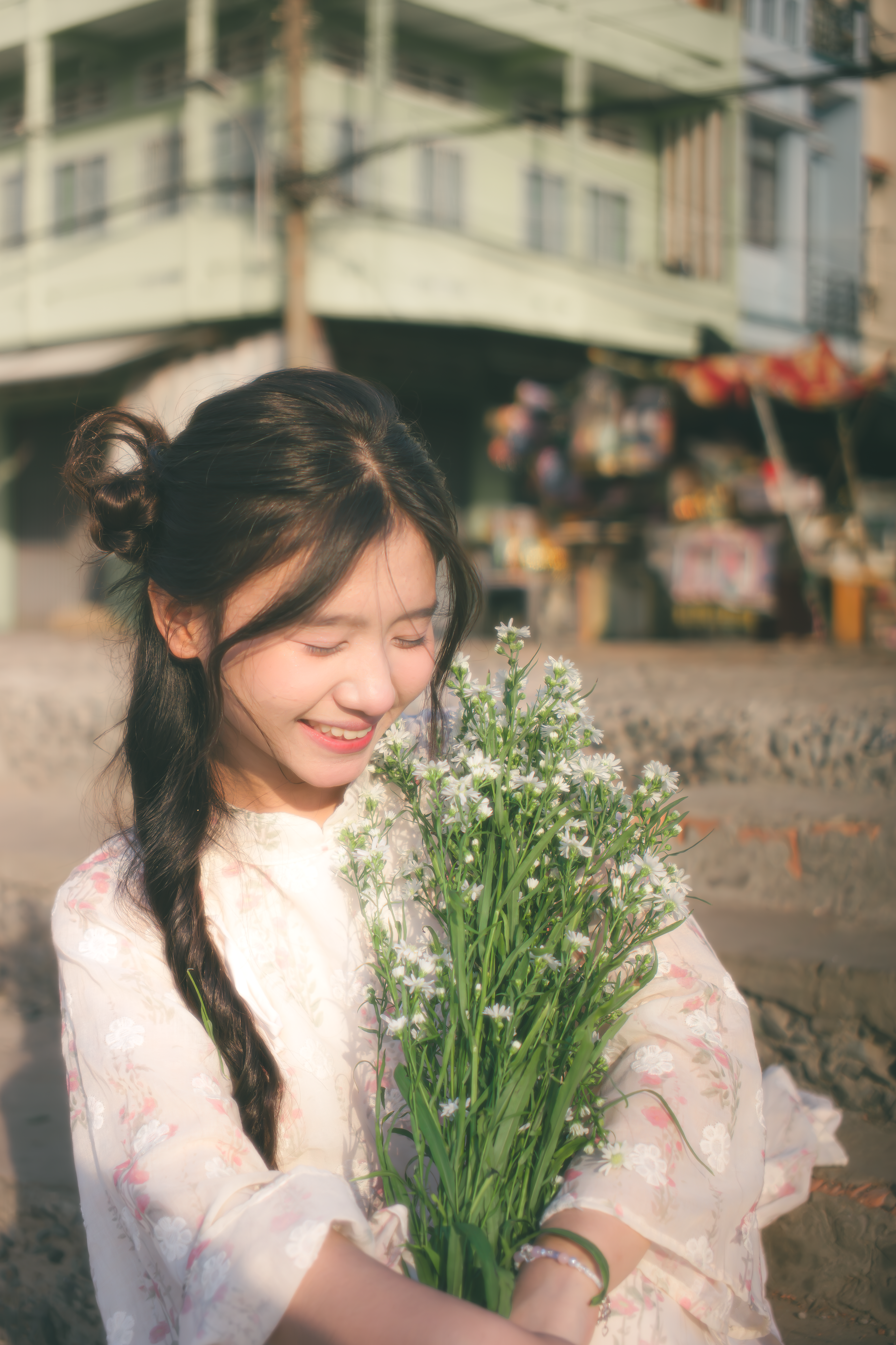 A joyful young woman holding flowers on a sunny day outdoors.