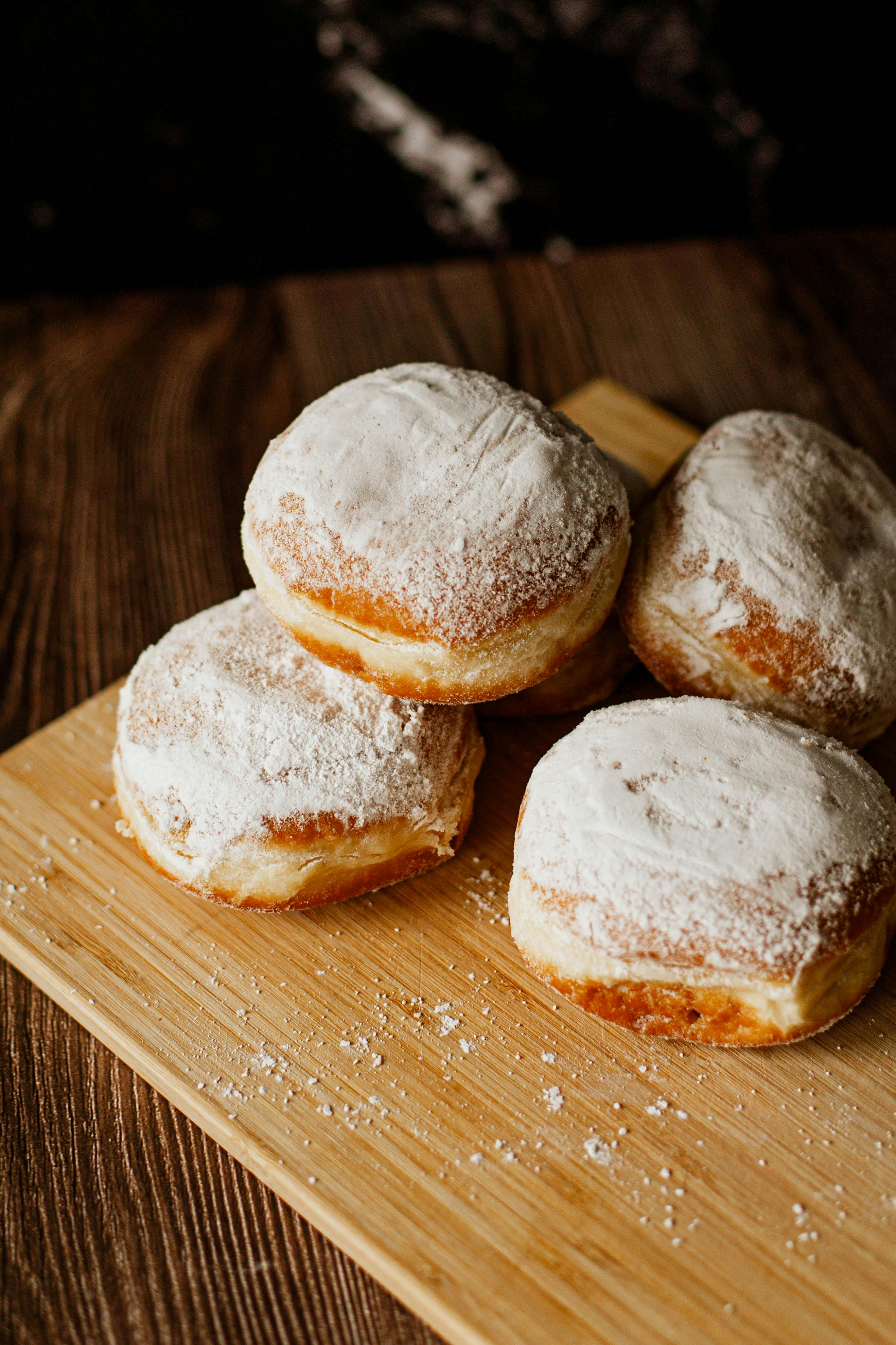 Close-up of delicious powdered donuts arranged on a wooden board, perfect for a sweet snack.