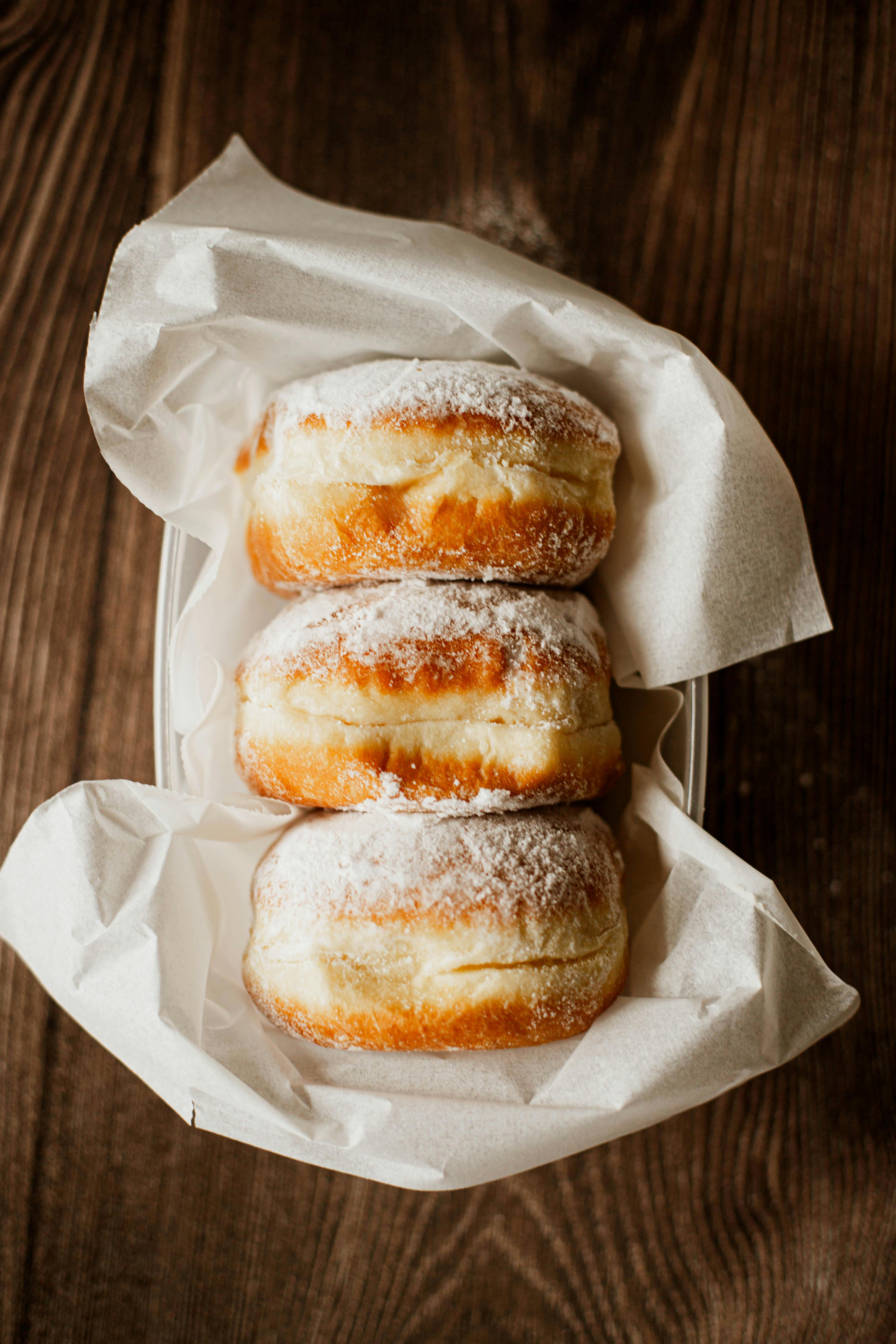 Three sugar-dusted donuts filled with cream, perfect for dessert lovers.