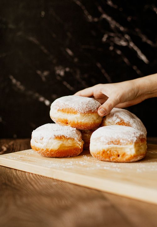 Free Close-up of fresh powdered donuts on a wooden board, perfect for bakery and dessert themes. Stock Photo