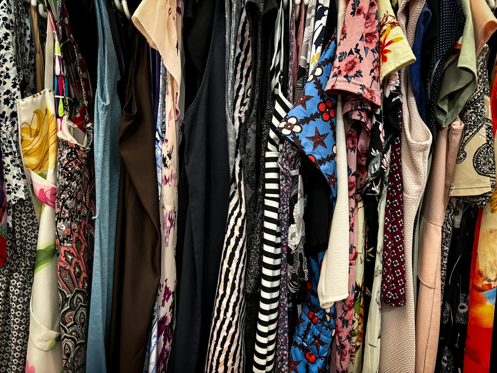 Vibrant collection of assorted vintage clothes hanging on a rack, showcasing patterns and styles.
