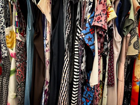 Vibrant collection of assorted vintage clothes hanging on a rack, showcasing patterns and styles.