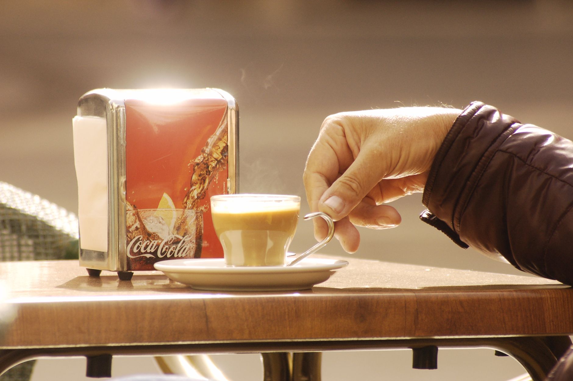 Hand holding coffee at an outdoor café in Murcia, Spain, enhancing a moment of warmth and relaxation.