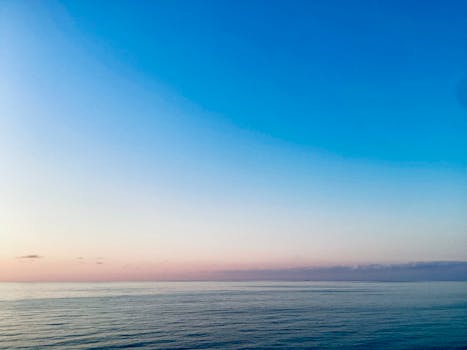 Serene view of the ocean at dawn with pastel sky colors creating a calming atmosphere.