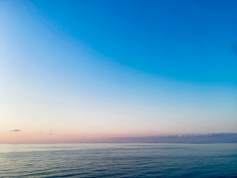 A serene ocean view at dawn with soft pastel sky - stillness and space