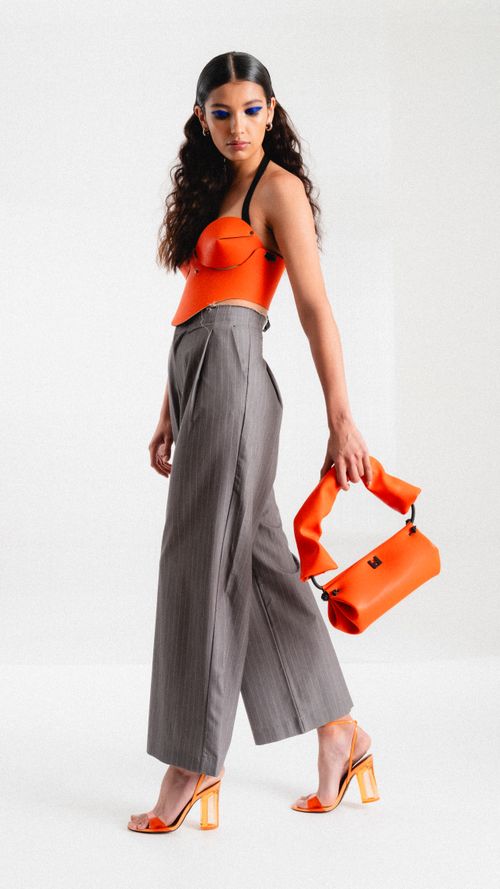 Free Stylish woman in orange top and handbag posing confidently. Modern fashion look. Stock Photo