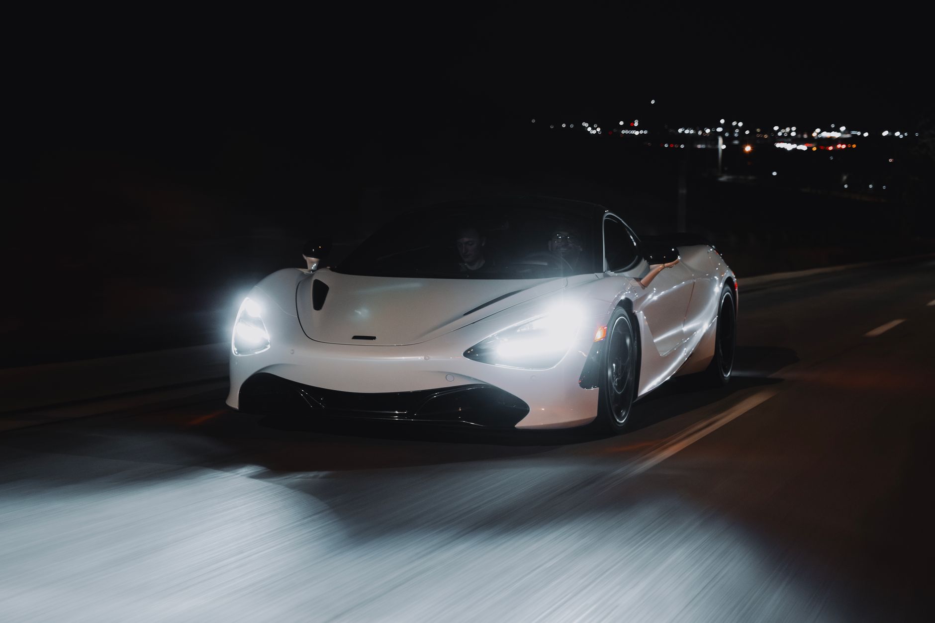 Dynamic shot of a white sports car driving through Calgary at night.