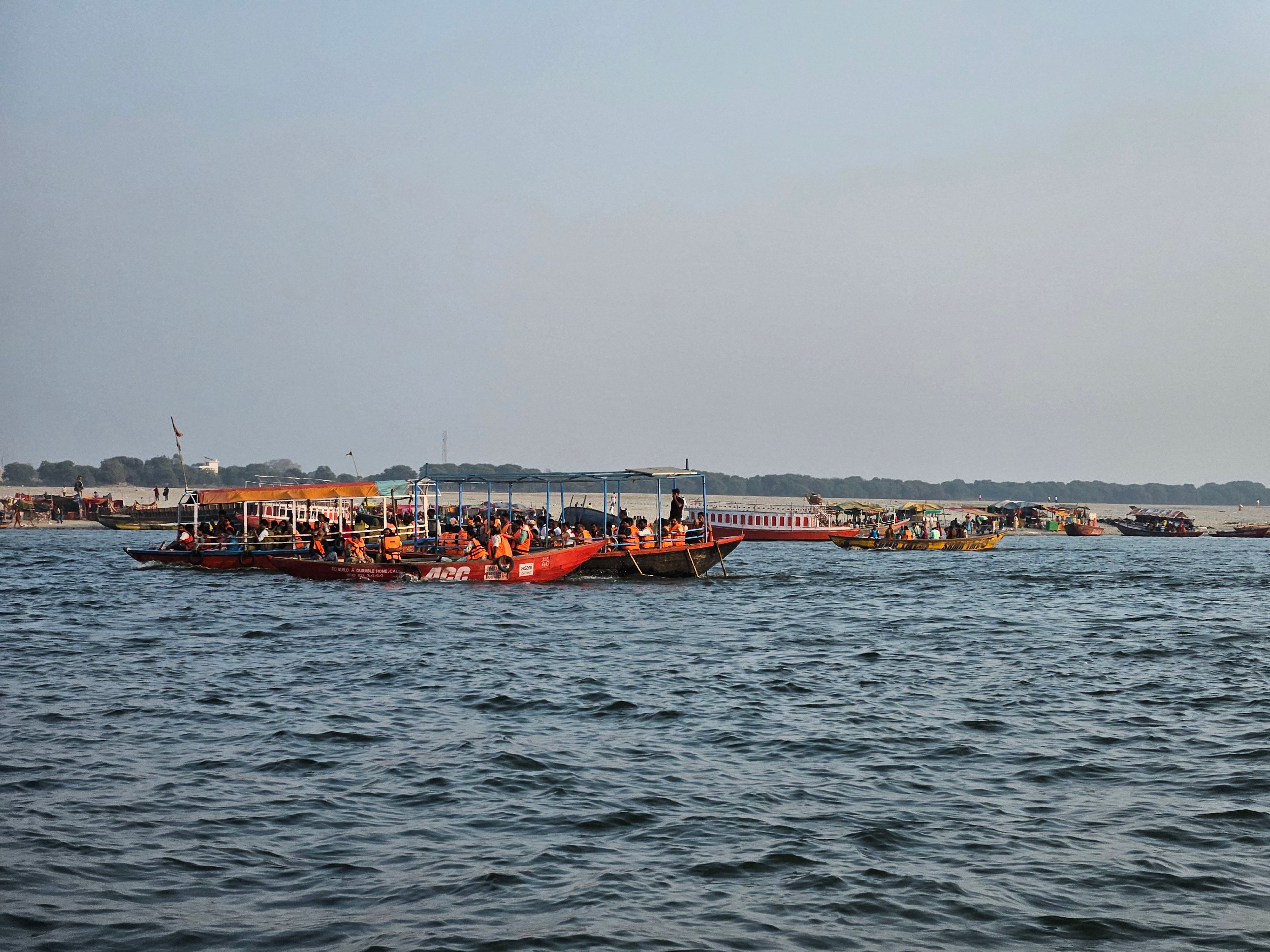A vibrant scene of boats on the Ganges River with people enjoying the serene atmosphere under a clear sky.