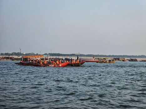A vibrant scene of boats on the Ganges River with people enjoying the serene atmosphere under a clear sky.