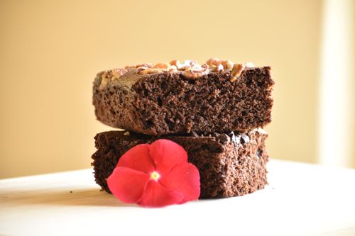 Free Close-up of chocolate brownies topped with nuts and a vibrant red flower. Stock Photo