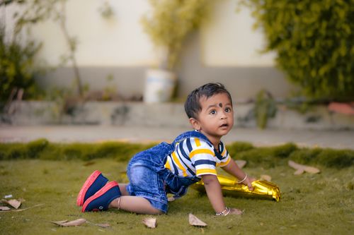 Free Capture of an adorable baby boy crawling on grass outdoors, exuding a playful and curious expression. Stock Photo