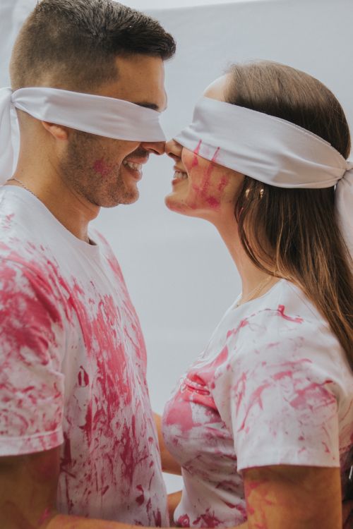 Free A joyful blindfolded couple with paint-stained clothes smiling at each other. Stock Photo