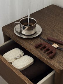 Stylish coffee setup with soaps and accessories on a wooden table.