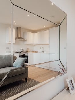 Stylish open-plan living room and kitchen with contemporary design and reflective surfaces.