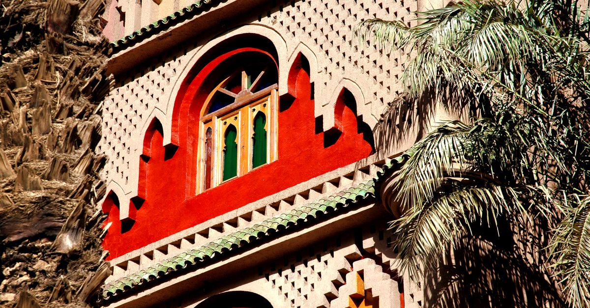 Ornate Moroccan building facade with traditional architecture and palm trees in Zagora.