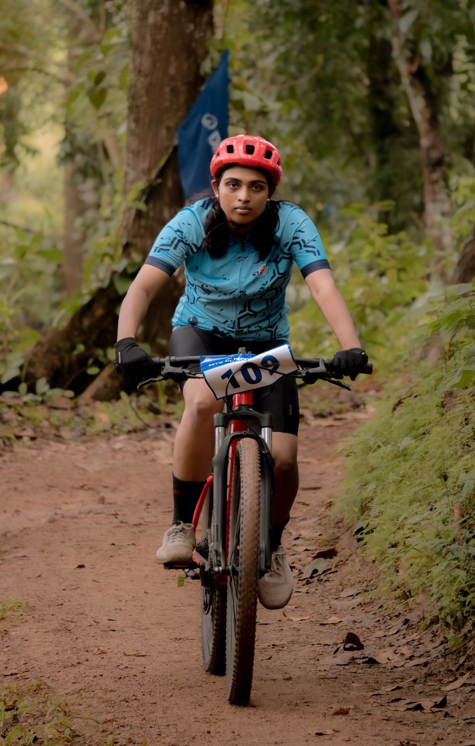 Female mountain biker descending a forest trail in helmet and protective gear