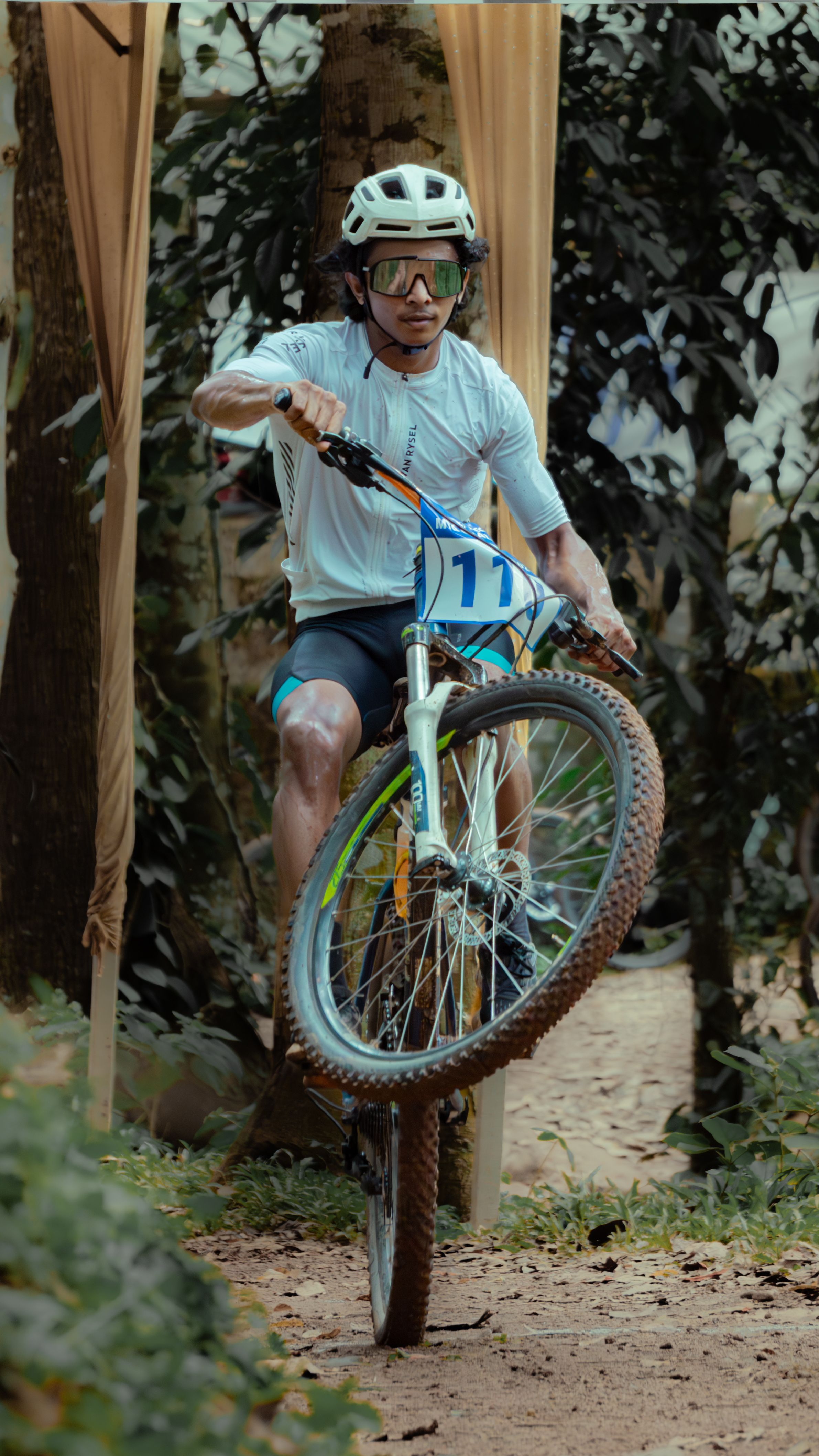 Mountain biker performing a thrilling wheelie during an off-road race.