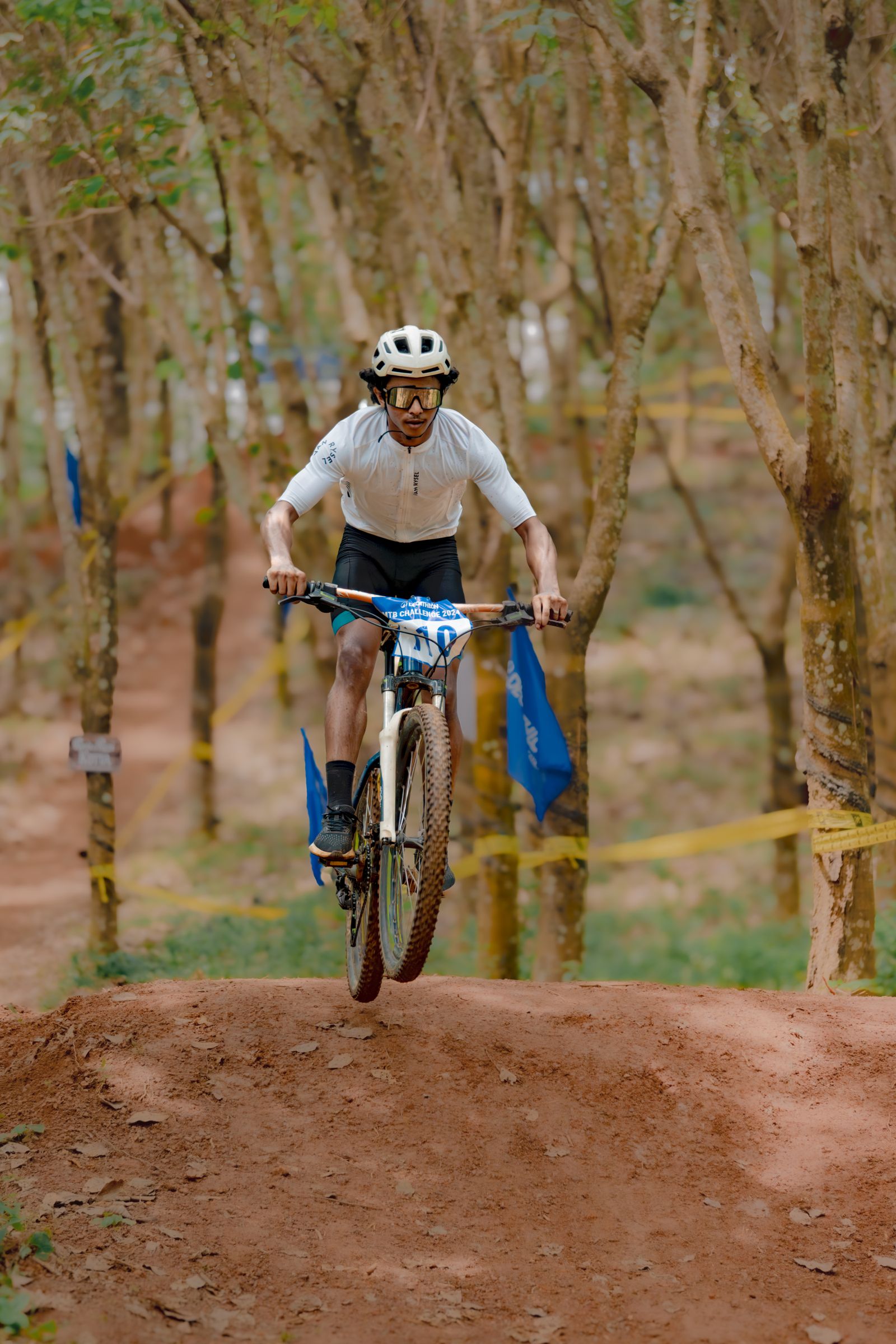 Mountain biker mid-air catching a jump on a forest trail