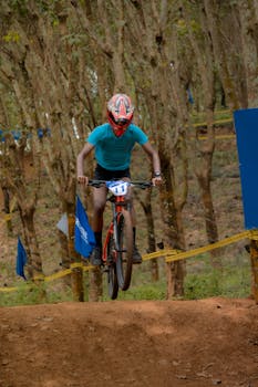 Mountain biker mid-air during thrilling ride on forest trail.