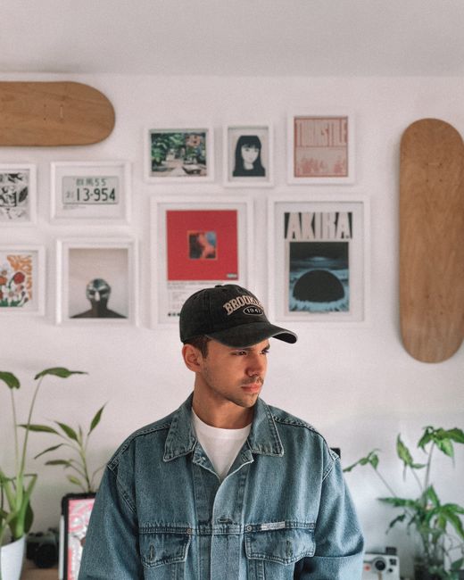 Young man in denim jacket in a decorated room with art and plants, Buenos Aires.
