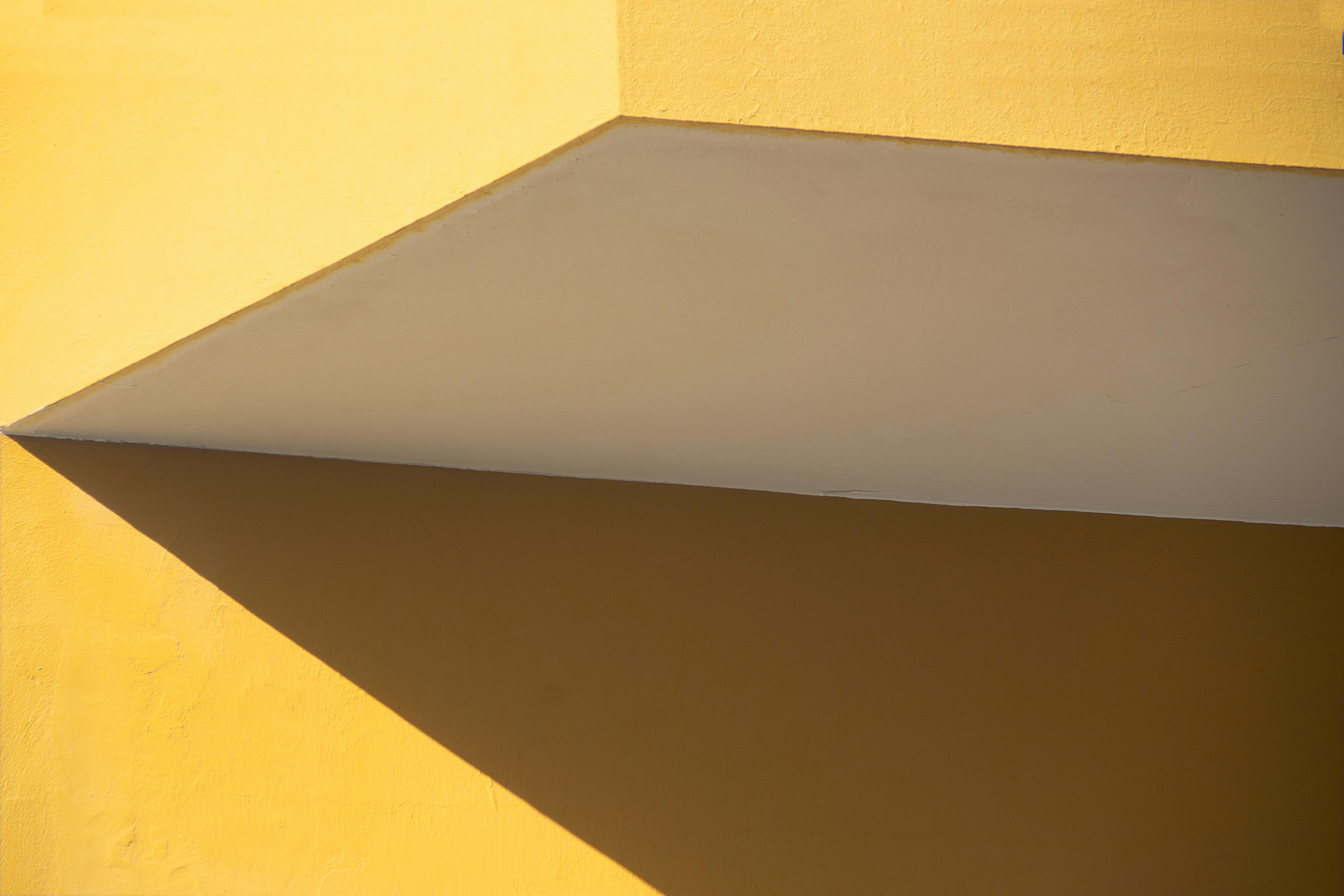 Ücretsiz Minimalist sarı cephe ve keskin gölgelerin yer aldığı soyut mimari görsel. Stok Fotoğraflar