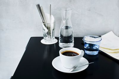 Cup of black coffee with a water carafe on a black cafe table