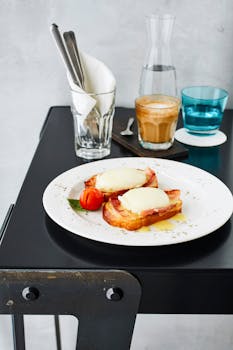 A perfect breakfast setting featuring eggs benedict, coffee, and utensils indoors.