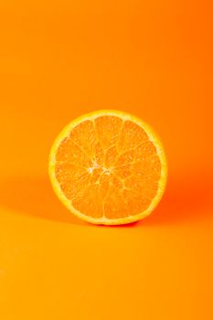 Bright and juicy orange slice photographed against an orange backdrop, highlighting its freshness.