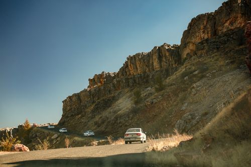 Free Cars navigate winding road in rocky mountain landscape under clear blue skies. Stock Photo