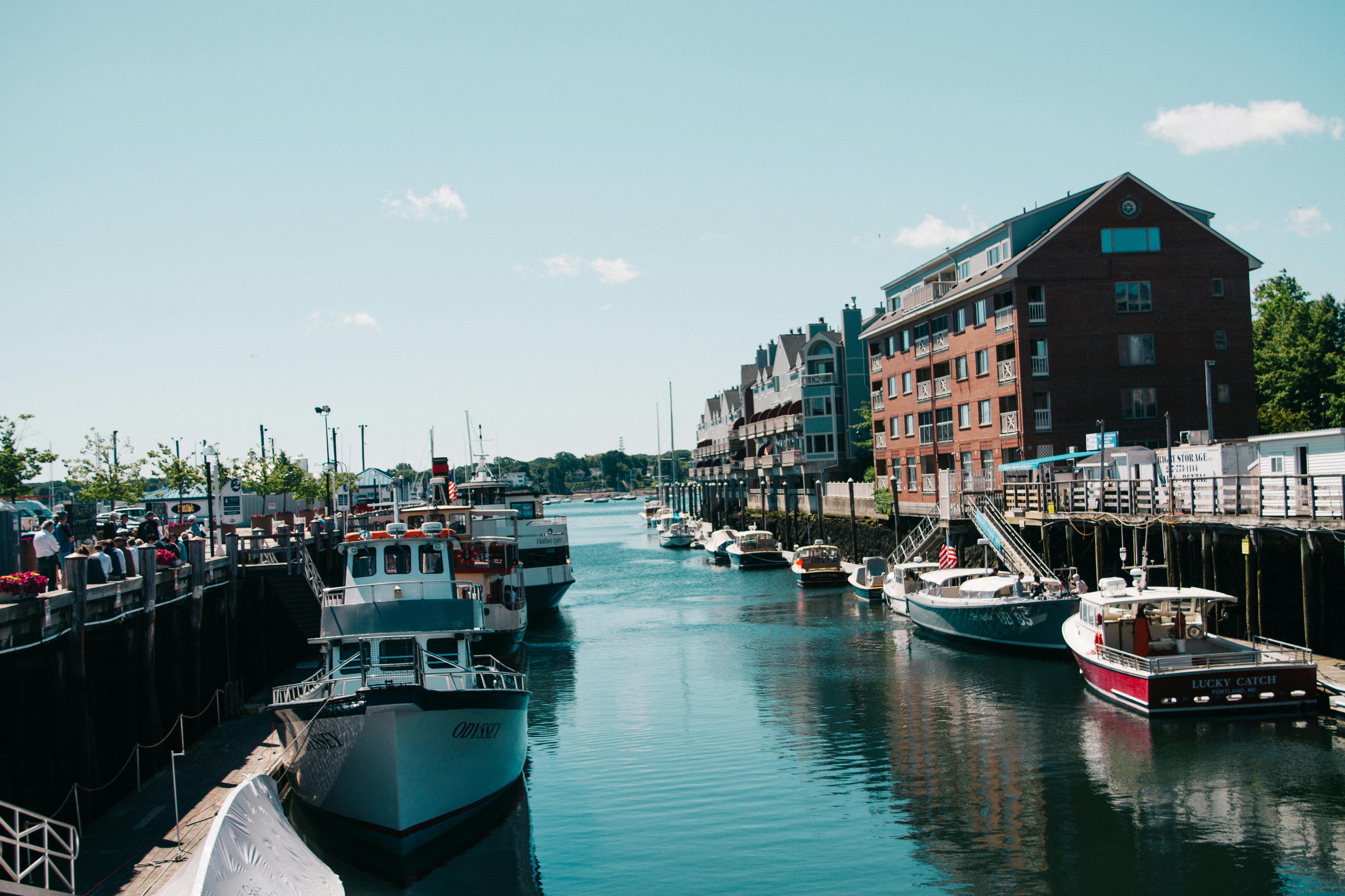 Free Scenic view of boats docked at a vibrant harbor beside brick buildings. Stock Photo