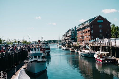 Free Scenic view of boats docked at a vibrant harbor beside brick buildings. Stock Photo