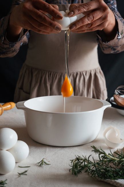 A person cracking an egg into a bowl, preparing ingredients for baking or cooking.