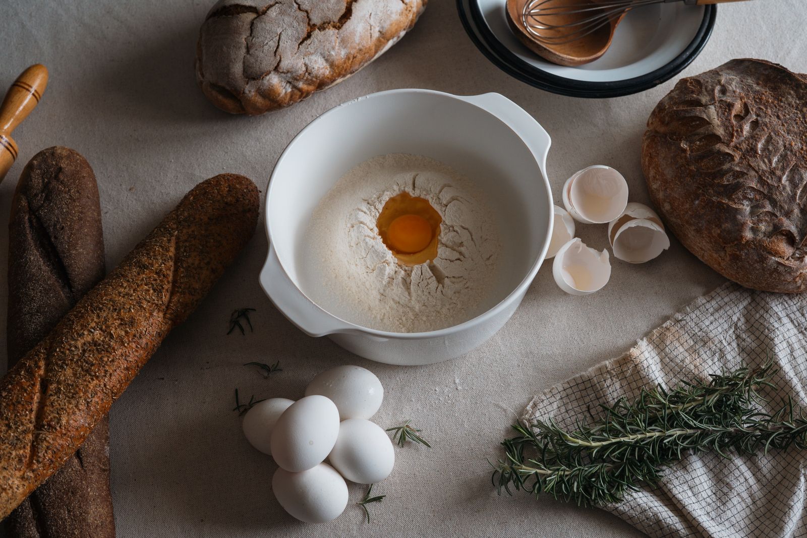 Top-down view of baking ingredients with bread, eggs, and flour in a homey kitchen setting.
