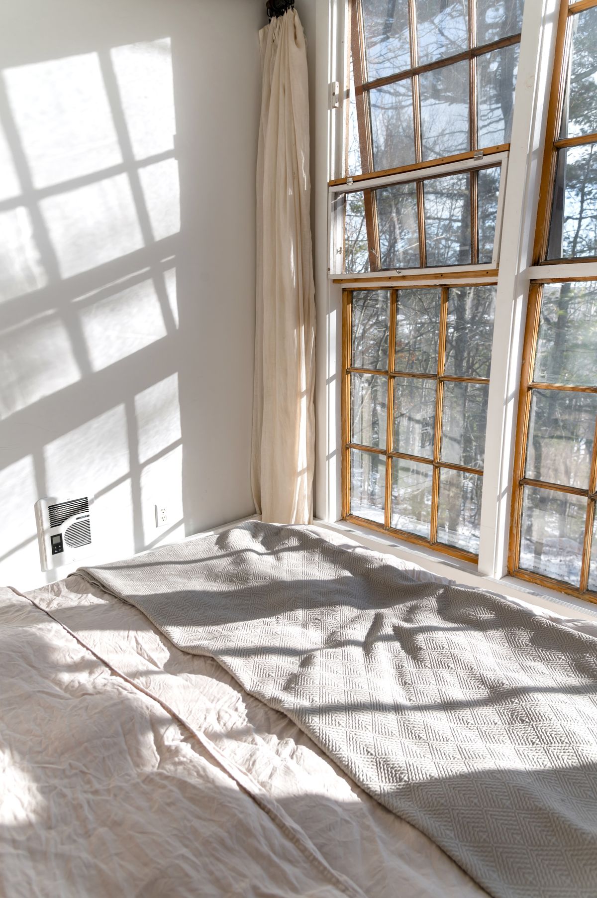 Sunlit bedroom with wooden windows and soft natural light on a made bed