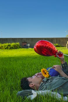 Romantic couple enjoying a sunny day in Buenos Aires park with heart balloon and sunflower.
