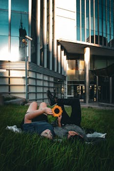 Couple lying on grass with sunflower in urban setting, Buenos Aires.